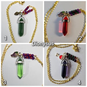 Puede incluir: Cuatro collares con cadenas doradas y colgantes tipo cristal. El colgante 1 es verde con una pi&ntilde;a. El colgante 2 es rojo con uvas. El colgante 3 es verde claro con uvas. El colgante 4 es morado con un dije en forma de copa de vino.