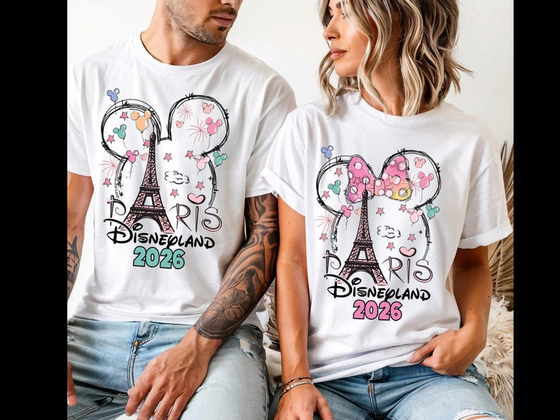May include: White t-shirts with a graphic design featuring the Eiffel Tower, Mickey Mouse ears, and the text "Paris Disneyland 2026". The design includes colorful accents like pink, blue, and green.