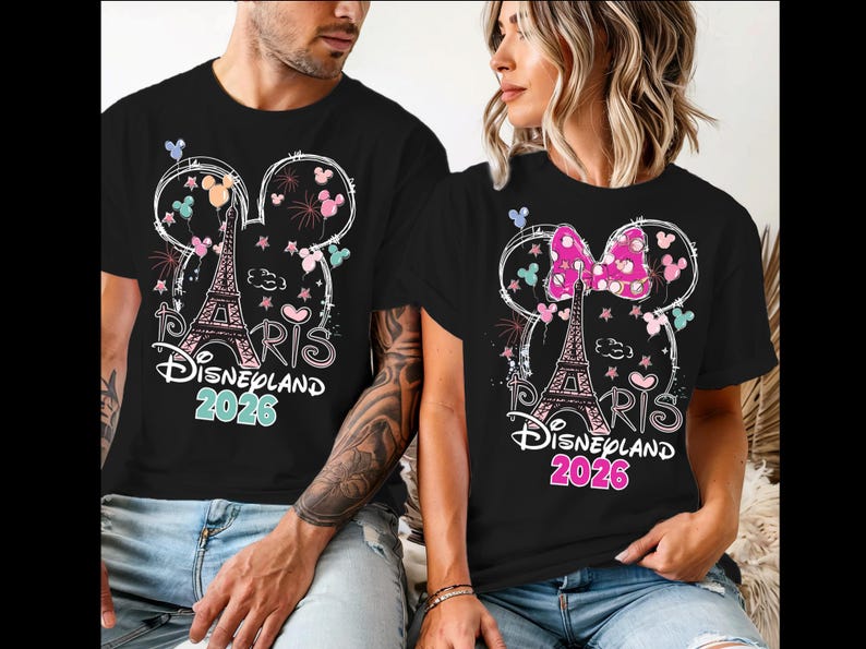May include: Black t-shirts with a Disneyland Paris 2026 design. The design includes the Eiffel Tower, Mickey Mouse ears, fireworks, and the text "Paris Disneyland 2026". One shirt has a pink bow.