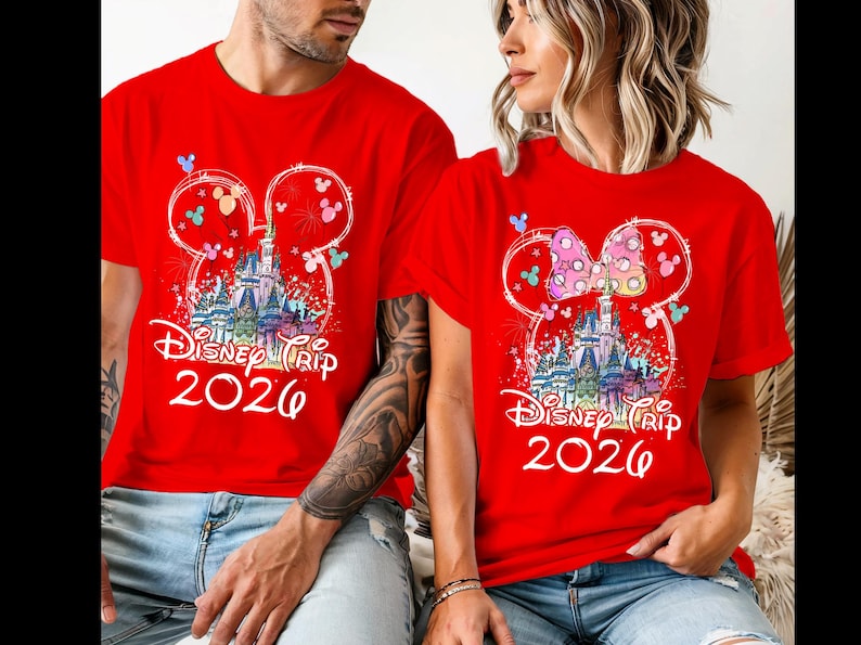 K&ouml;nnte beinhalten: Rote T-Shirts mit einem Disney Trip 2026 Design. Das Design zeigt ein Schloss, Feuerwerk und Mickey Mouse Ohren. Ein Shirt hat eine Schleife auf den Ohren. Die Shirts werden von zwei Personen getragen.