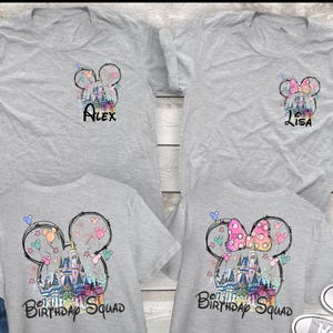 Może przedstawiać: Cztery szare koszulki z motywami Myszki Miki i Myszki Minnie. Dwie koszulki mają imiona "Alex" i "Lisa". Pozostałe dwie koszulki mają napis "Birthday Squad" z grafiką zamku. Wzory są kolorowe.