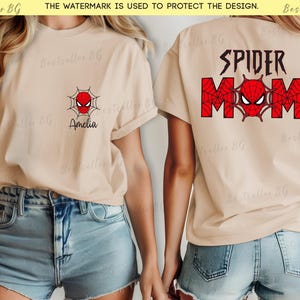 Puede incluir: Camiseta beige con un dise&ntilde;o de Spider-Man. La parte delantera presenta un dise&ntilde;o de telara&ntilde;a roja y negra con una cara de ara&ntilde;a y el nombre "Amelia". La parte trasera de la camiseta tiene las palabras "SPIDER MOM" con una cara de ara&ntilde;a.