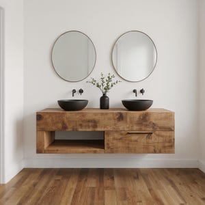 May include: A rustic wooden bathroom vanity with two black bowl sinks and matching black faucets. Two round mirrors with gold frames hang above the sinks. A small black vase with greenery sits between the sinks. The vanity has a drawer and an open shelf.