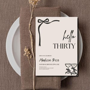 Puede incluir: Una tarjeta de invitaci&oacute;n beige con texto negro y un dise&ntilde;o de lazo. Las palabras "hello THIRTY" se muestran de forma destacada. La invitaci&oacute;n incluye detalles para una celebraci&oacute;n, con el nombre "Madison Rose" e informaci&oacute;n del evento.