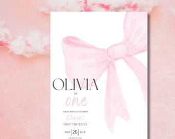 以下が含まれることがあります： 白い背景にピンクの水彩画のリボン。リボン下に「Olivia is one」の文字が印刷されています。「Please join us to celebrate Olivia's First Birthday」の文字が「Olivia is one」の文字下に印刷されています。「May 28 | 12-2」の文字がテキスト下に印刷されています。「The Bow Cottage」の文字が日付下に印刷されています。