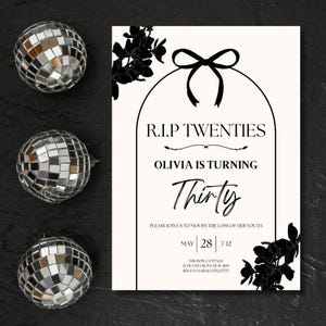 May include: A party invitation with the text "R.I.P Twenties, Olivia is Turning Thirty" in black font. The invitation is decorated with black floral accents and a black bow. Three silver disco balls are on the left side of the invitation.
