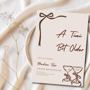 May include: A beige invitation card with brown text and a decorative bow. The text reads "A Tini Bit Older" and includes details for an event, including the name "Madison Rose" and the date and time.