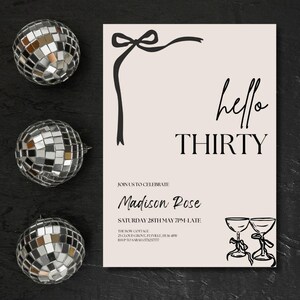 Puede incluir: Una invitaci&oacute;n de fiesta beige con el texto "hello THIRTY" y detalles del evento. La invitaci&oacute;n tiene un dise&ntilde;o de lazo negro y texto. Tres bolas de discoteca est&aacute;n en el lado izquierdo de la imagen.