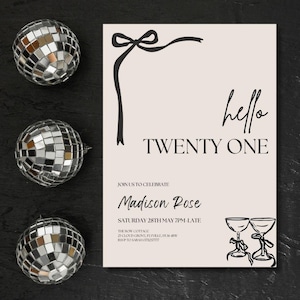 May include: An invitation card with the text "hello TWENTY ONE" in black script. The card has a beige background with a black bow and ribbon design. Three disco balls are arranged around the card on a black surface.