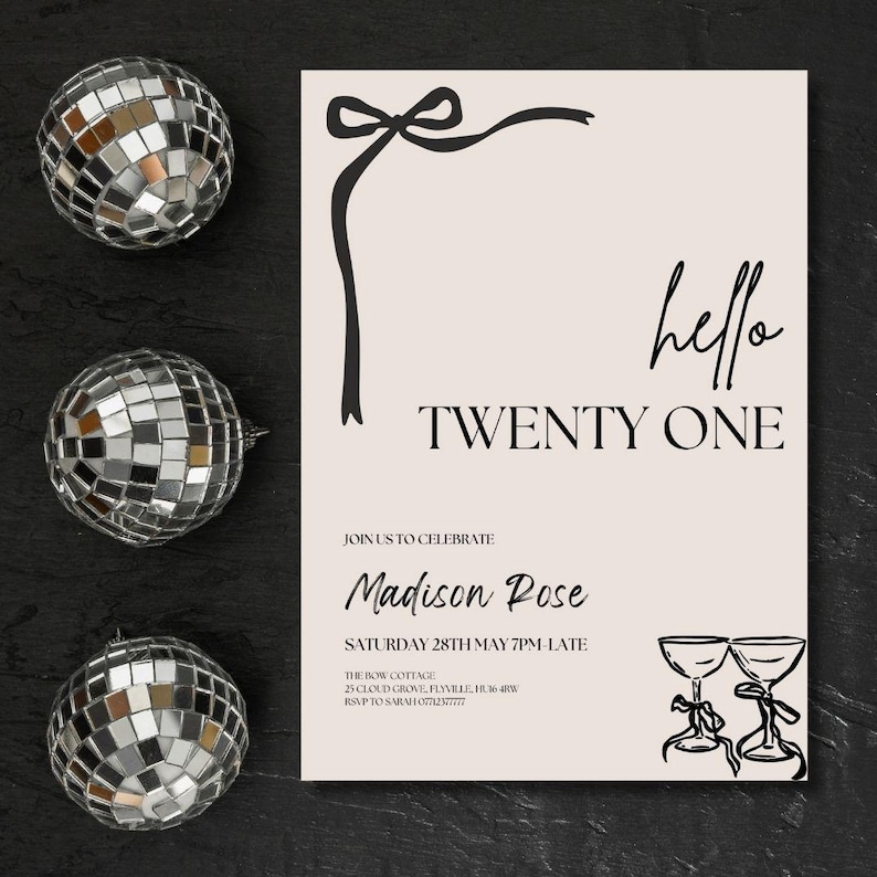 May include: An invitation card with the text "hello TWENTY ONE" in black script. The card has a beige background with a black bow and ribbon design. Three disco balls are arranged around the card on a black surface.