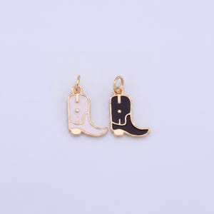 May include: Two gold-colored metal charms in the shape of cowboy boots. One boot is white with a gold outline, and the other is black with a gold outline. Both charms have a small loop at the top for attaching to a chain or bracelet.