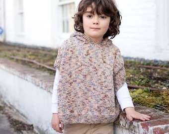 May include: A young person wearing a hooded, multi-colored knitted poncho with a white long-sleeved shirt underneath. The poncho has a speckled pattern of brown, pink, and purple.
