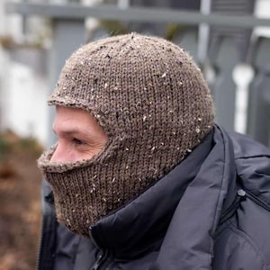 May include: A brown knitted balaclava with a textured pattern. The balaclava covers the head and face, with eye holes and a mouth opening.