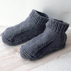 May include: A pair of gray knitted slipper socks. The socks are made with a simple knit stitch and have a soft, cozy feel.