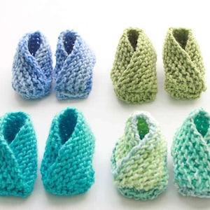 Puede incluir: Seis pares de botines de bebé tejidos en colores azul, verde y turquesa. Los botines están hechos con un patrón de punto simple y tienen un puño doblado.