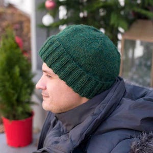 May include: A dark green knitted beanie with a ribbed brim. The beanie is made of a soft, textured yarn.