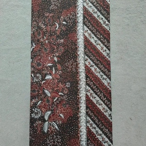 Könnte beinhalten: Ein brauner und silberner Stoff mit einem Blumenmuster und einem diagonalen Streifenmuster. Der Stoff hat einen silbernen Rand.