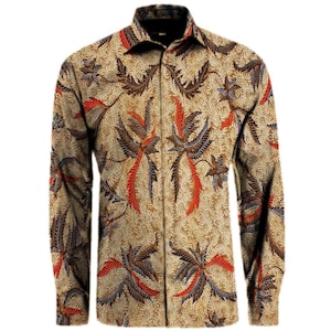 Op de afbeelding: Een overhemd met lange mouwen en knoopsluiting, voorzien van een beige achtergrond met een gedetailleerd batik-patroon in tinten bruin, donkergrijs en feloranje. Het ontwerp bestaat uit herhalende blad- en bloemmotieven over het hele kledingstuk.