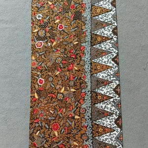 May include: A brown and white fabric with a floral pattern. The fabric has a border of white triangles with a black outline.