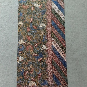 Peut inclure: Un panneau de tissu rectangulaire avec un motif batik coloré. Le motif présente un design floral avec des couleurs bleues, rouges, blanches et vertes. Le tissu a une texture lisse.