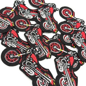 May include: A group of red and black embroidered motorcycle patches. The patches are detailed with white stitching and feature a motorcycle design.
