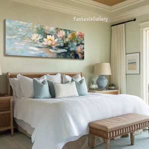 May include: A white bed with a white duvet cover and a brown wicker headboard. The bed has a white bedspread and a brown wicker bench at the foot of the bed. There is a painting of pink water lilies on the wall above the bed.