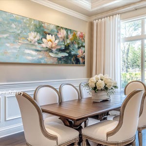 May include: A painting of white water lilies in a pond with a blue and green background. The painting is hanging on a wall in a dining room with a wooden table and white chairs.