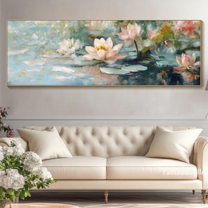 May include: A painting of white water lilies with pink accents on a blue and green background. The painting is framed and hanging on a wall above a white couch.