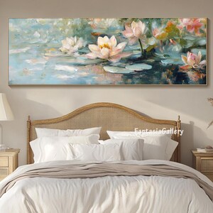 May include: A painting of white water lilies with pink accents on a blue and green background. The painting is framed and hanging above a white bed with a wooden headboard.