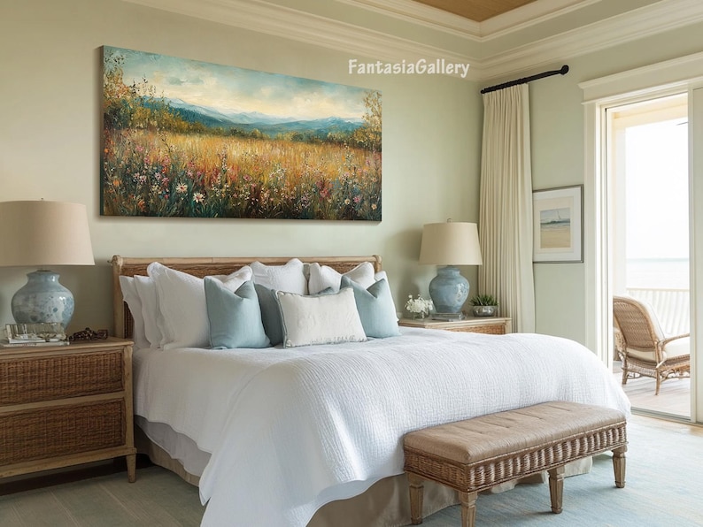 May include: A white bed with a light blue and white patterned headboard and a white duvet cover. The bed is in a bedroom with a large painting of a field of wildflowers hanging above the headboard. There is a wicker nightstand next to the bed and a wicker bench at the foot of the bed.