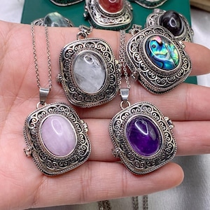 Può includere: Collane argentate con pendenti quadrati e ornati. Ogni pendente presenta una gemma diversa, tra cui rosa, viola e abalone iridescente. I pendenti sono attaccati a delicate catene d'argento, mostrando gioielli colorati e accattivanti.