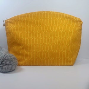 May include: A yellow zippered pouch with a wheat pattern. The pouch is made of fabric and has a white zipper.
