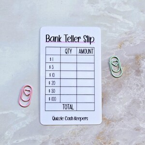 May include: A white bank teller slip with the text "Bank Teller Slip" in black and pink. The slip has columns for quantity and amount, with denominations from $1 to $100. Two paper clips, one pink and one green, are next to the slip.