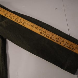 Puede incluir: Manga de chaqueta verde oscuro con dos bolsillos y una regla de madera que mide hasta 63.5 cm. La regla est&aacute; marcada con el texto "WILLIAM VOLKER & COMPANY".