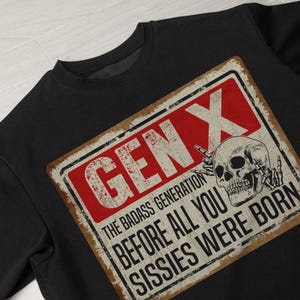 May include: Black sweatshirt with a vintage-style sign that reads "Gen X The Badass Generation Before All You Sissies Were Born" with a skull graphic.