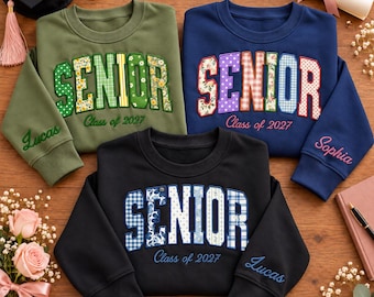 May include: Three crewneck sweatshirts in olive green, navy blue, and black. Each features the word SENIOR in patterned applique letters, the text Class of 2027, and a personalized name embroidered on the sleeve cuff in cursive script.