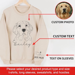 May include: Beige sweatshirt with a line drawing of a golden retriever dog and the name "Bailey" printed below. The text "DOG MOM" is printed on the sleeve. The sweatshirt can be customized with a photo and text.