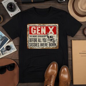 May include: Black t-shirt with a vintage-style sign that reads "Gen X The Badass Generation Before All You Sissies Were Born". The sign has a skull with a middle finger and is set against a red and white background.