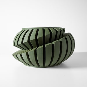 May include: A green ceramic planter with a unique geometric design. The planter is made of multiple overlapping layers of curved, vertical lines.