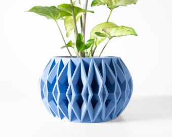 May include: A light blue geometric planter with a plant growing out of it. The planter has a diamond pattern and is made of a smooth material.