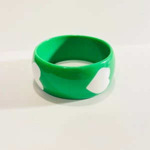 Green plastic bangle bracelet with white pop art hearts