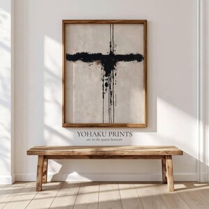 May include: A framed abstract wall art print featuring a black ink cross shape with vertical drips on a textured off-white background. The text YOHAKU PRINTS art in the spaces between is printed in black below the wooden frame of the artwork.