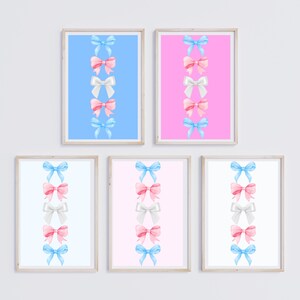 Op de afbeelding: Set van zes printbare wandkunstprints met een verticale rij van vijf aquarel linten in afwisselende kleuren roze, blauw en wit. De prints zijn ingelijst in een eenvoudige, licht houten lijst.