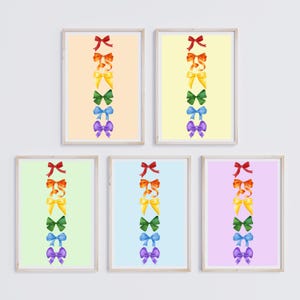 Op de afbeelding: Vijf ingelijste prints met een regenboog van strikken op elk. De strikken zijn verticaal gerangschikt van rood naar paars. De frames zijn allemaal even groot en even gevormd, en ze zijn allemaal wit.