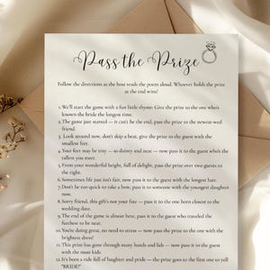 May include: A printed wedding game card titled "Pass the Prize" with a diamond ring graphic. The card features instructions for a bridal shower game, printed in black ink on a cream-colored paper. The card is placed on a neutral-toned envelope.