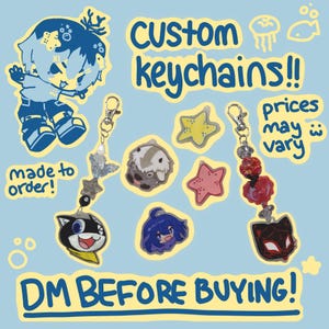 May include: Image of custom keychains featuring cartoon character designs, including a cat, a girl, and a dog. The keychains are attached to silver clasps and decorated with beads and charms. Text on the image reads "Custom Keychains!!" and "DM Before Buying!"
