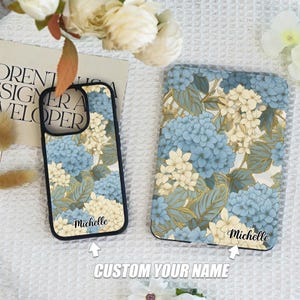 May include: Two phone cases with a floral design featuring blue and white hydrangeas. The cases have a customizable name option, with the name "Michelle" printed on each case.