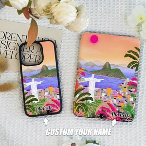 May include: Two phone cases with a colorful illustration of the Christ the Redeemer statue in Rio de Janeiro, Brazil. The cases are black and have a white name "Michelle" printed on the bottom. The text "CUSTOM YOUR NAME" is printed below the cases.