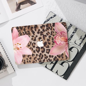 May include: A laptop skin with a leopard print background and pink orchid and lily flowers. The skin is designed to fit a laptop computer.