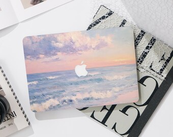 May include: A laptop case featuring a seascape painting with a sunset sky and ocean waves in shades of blue, pink, and orange. The Apple logo is visible on the case. The case is resting on a patterned surface.